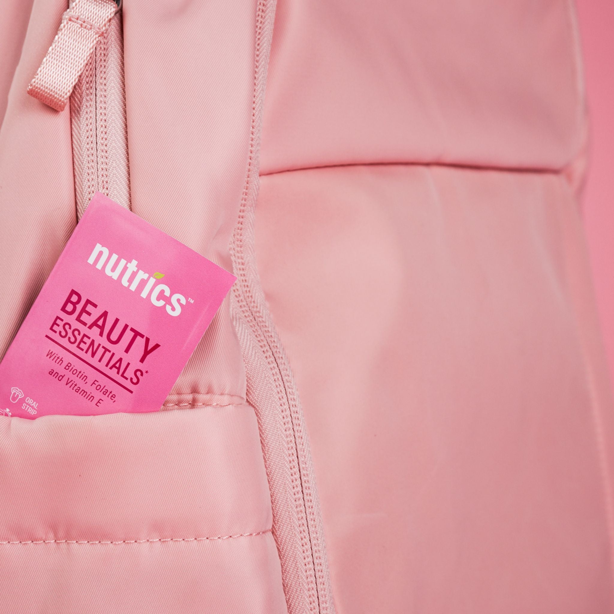 Pink jacket with a Nutrics Beauty Essentials packet in the pocket on a pink background